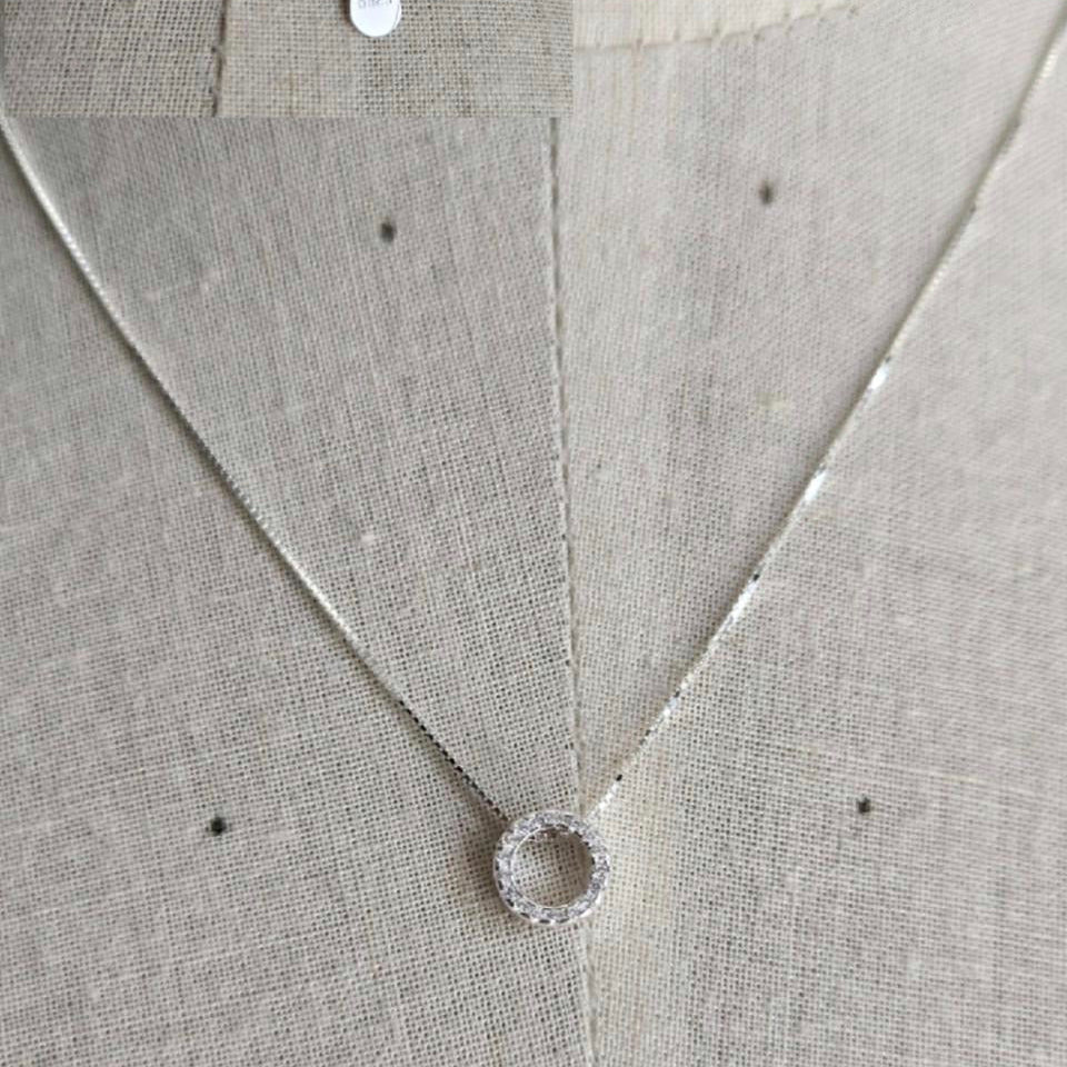 Silver necklace with a pendant on a textured gray fabric background