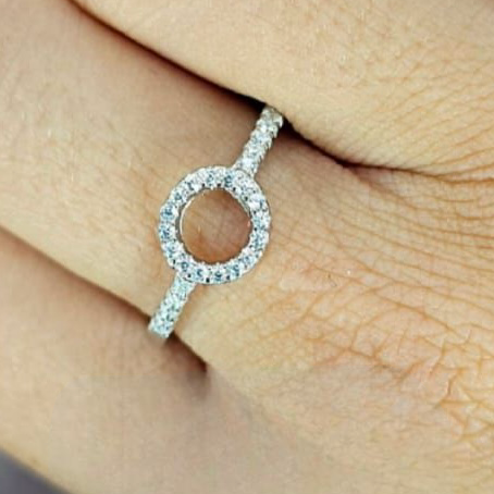 A person's hand displaying a sterling silver ring with a Pavé circle design, adorned with cubic zirconia stones.