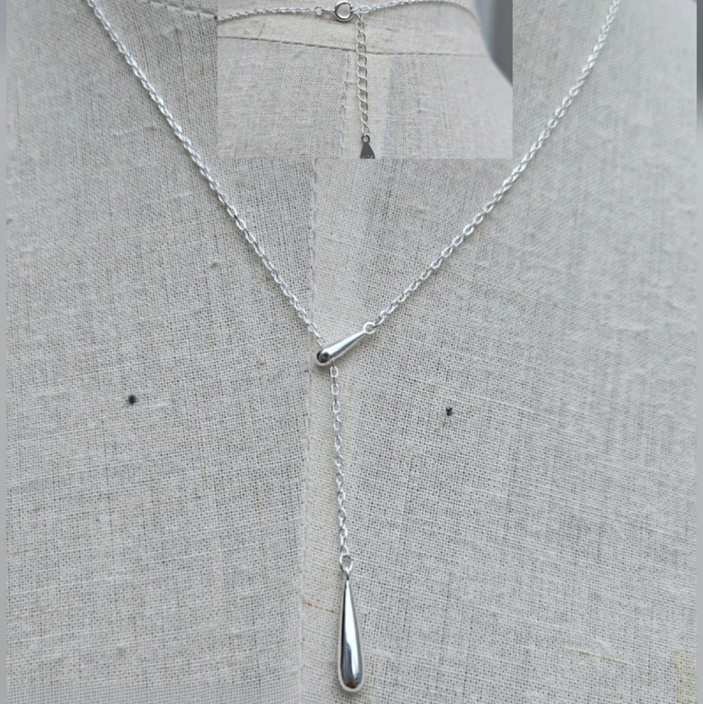 Silver necklace with a pendant on a gray fabric background