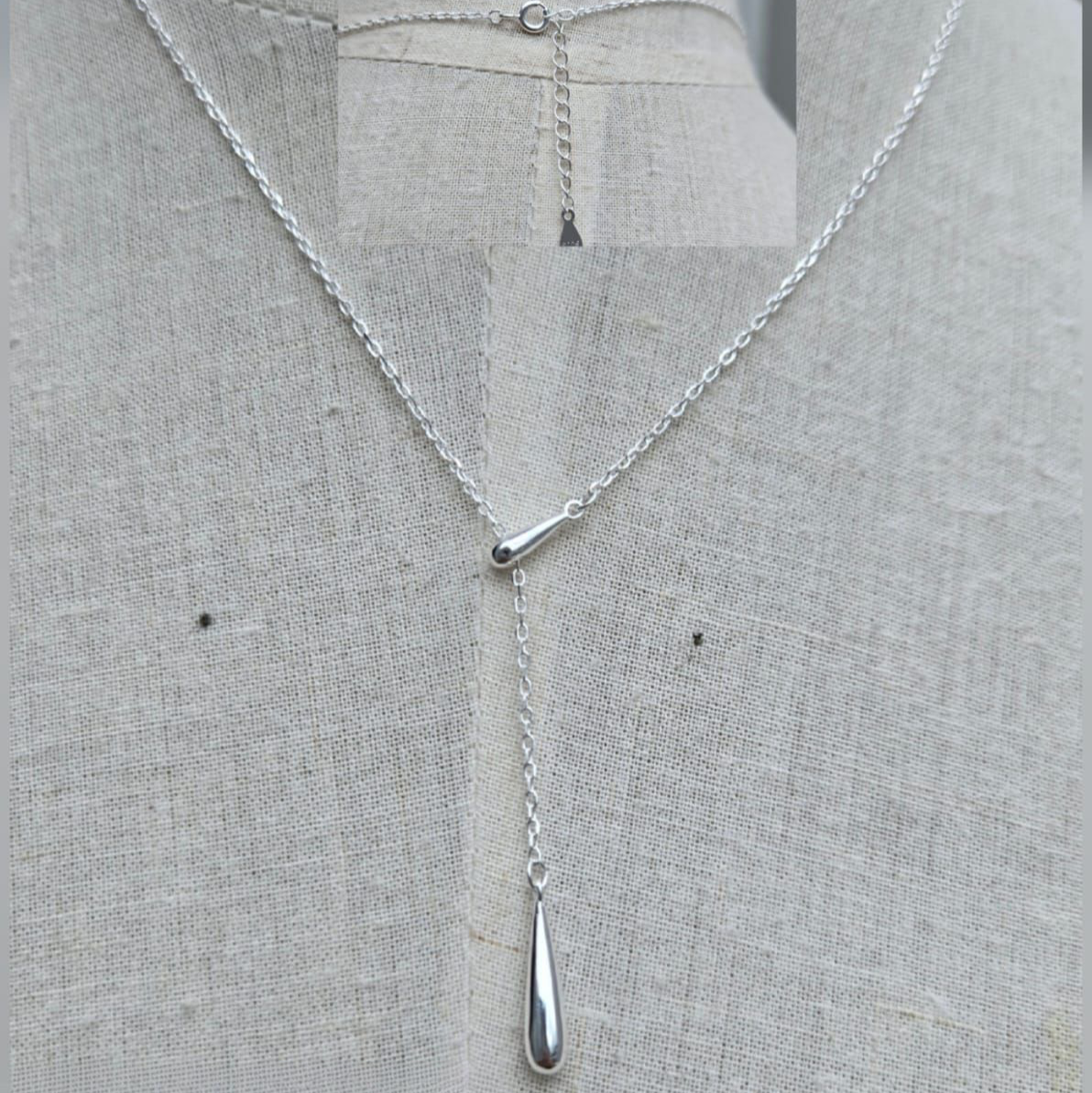 Silver necklace with a pendant on a gray fabric background