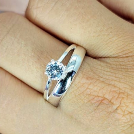A double band ring with a cubic zirconia centerpiece is displayed on a person's finger.