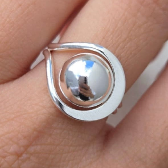 Silver ring on a finger against a neutral background