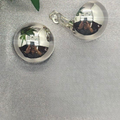 A close-up image of a person wearing a pair of sterling silver clip-on earrings.