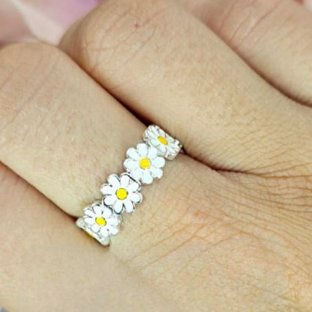 An adjustable sterling silver daisy ring worn on a person's finger, showcasing a classic yet modern floral design.