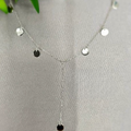 A V-shaped necklace with dangling silver discs displayed on a mannequin.