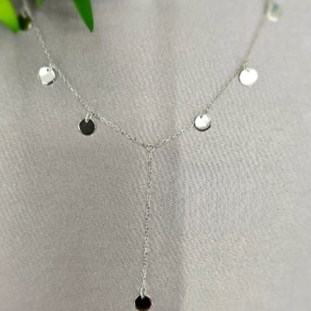 A V-shaped necklace with dangling silver discs displayed on a mannequin.