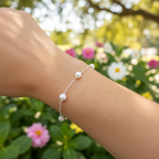 A sterling silver bracelet with freshwater pearls in a link pattern, displayed on a person's wrist.