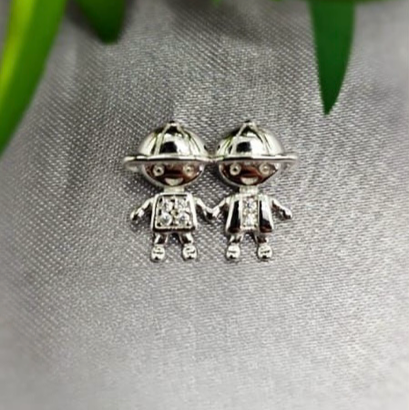 A sterling silver pendant featuring two boy figures with cubic zirconia accents, displayed against a fabric background.