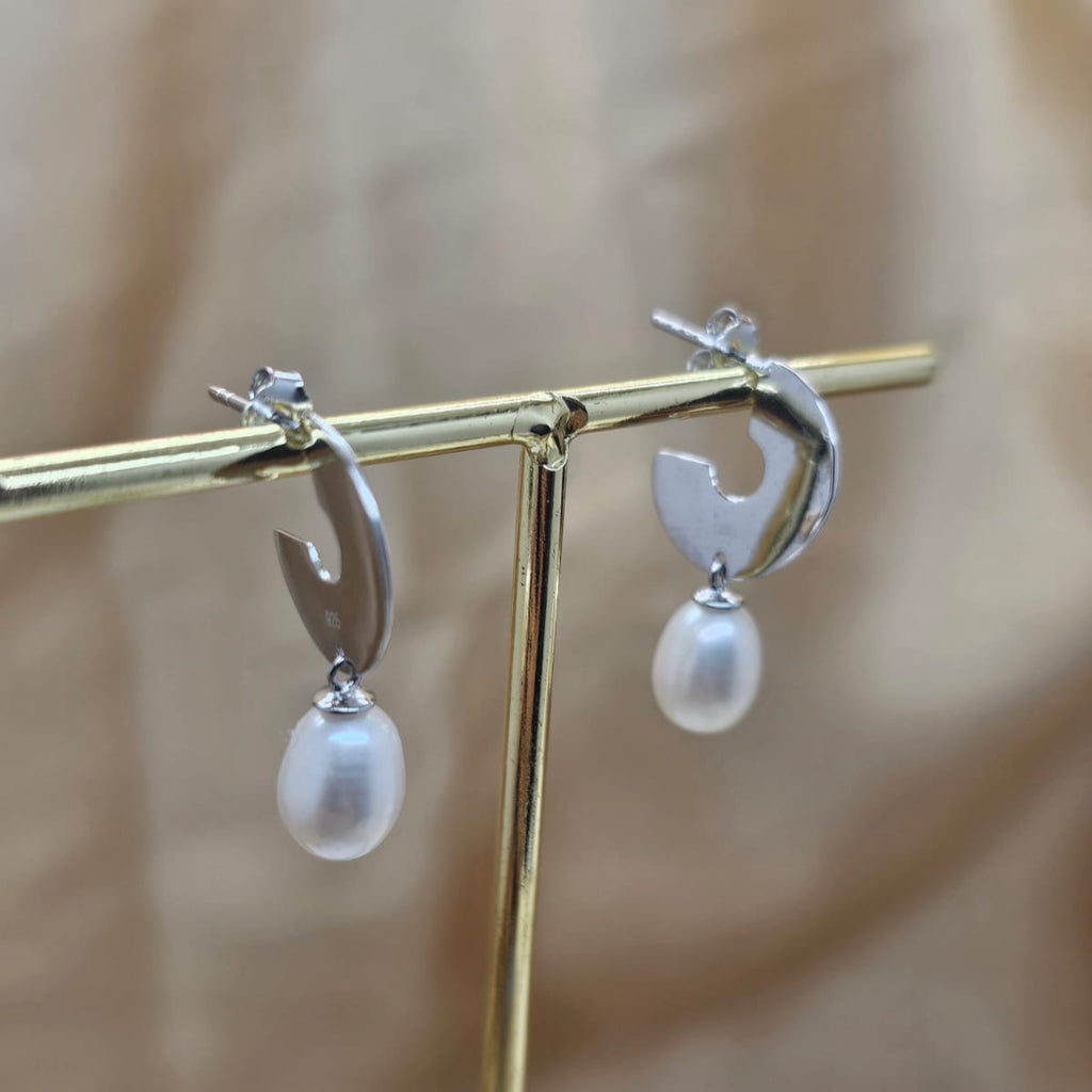 Pearl earrings on a gold stand with a blurred background