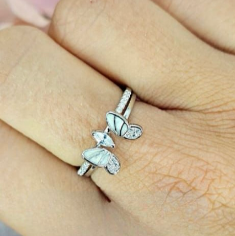 A woman's hand displaying a sterling silver ring with a butterfly design and cubic zirconia centers.