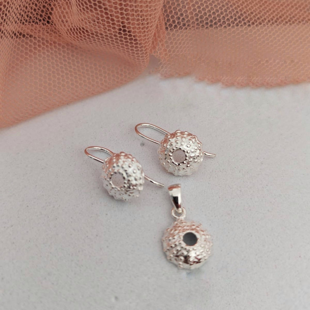 Silver jewelry set with spherical designs on a light background