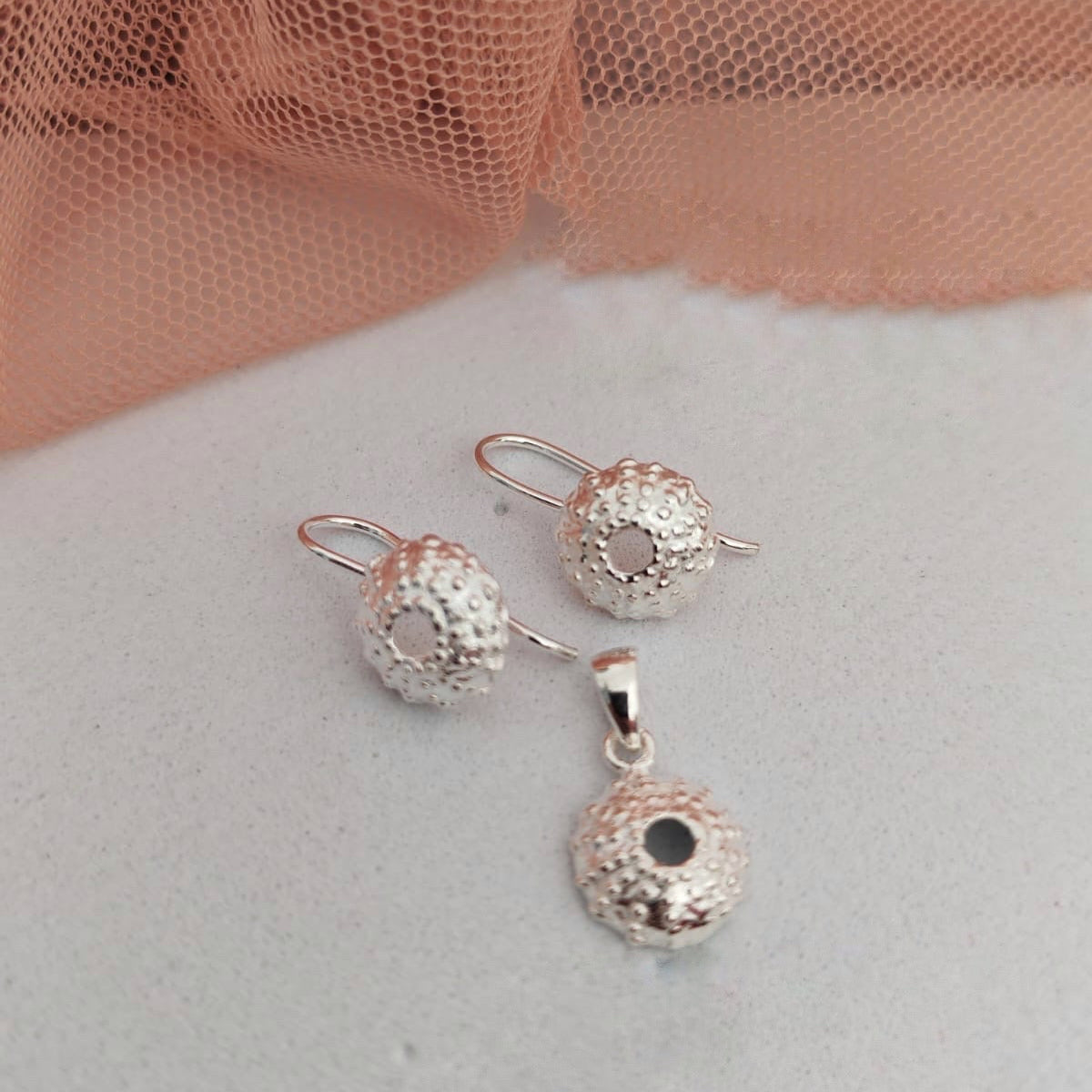 Silver jewelry set with spherical designs on a light background