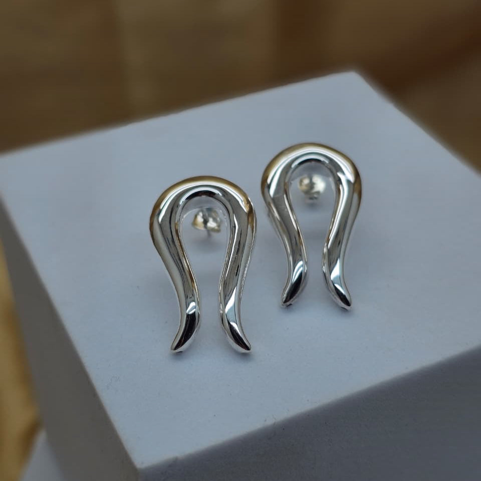 Silver earrings on a white box with a blurred background