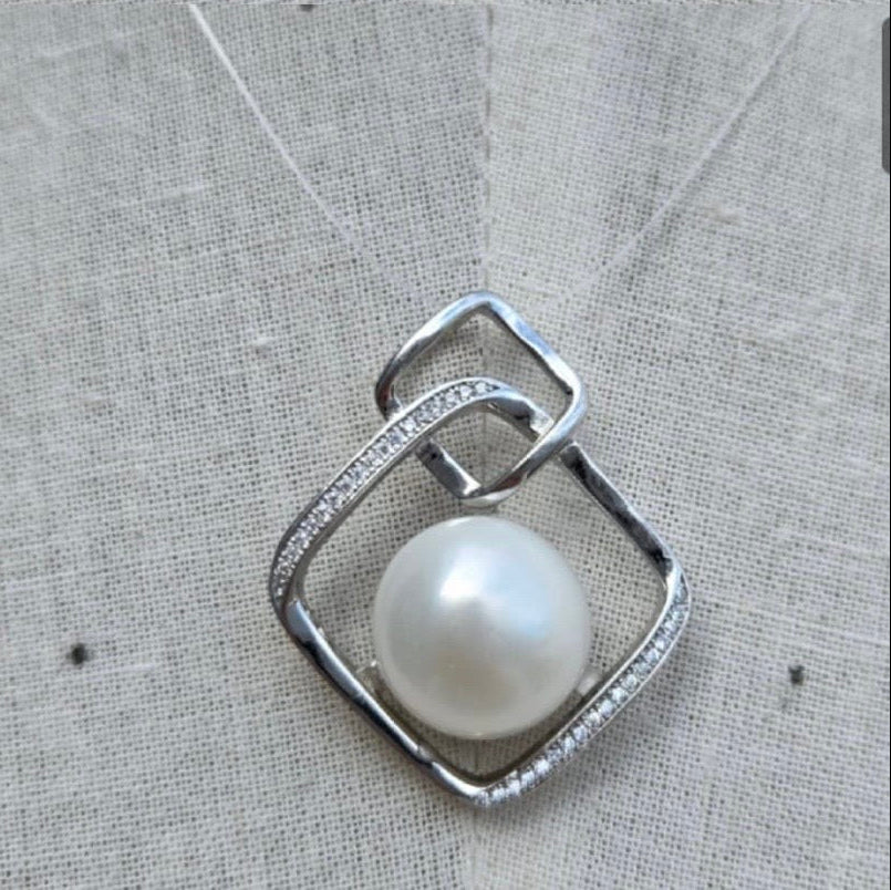 Silver pendant with a pearl on a textured fabric background