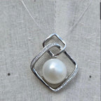Silver pendant with a pearl on a textured fabric background
