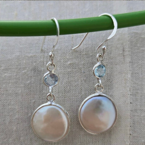 Pair of silver earrings with round stones on a gray background