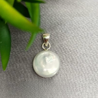 A sterling silver pendant featuring a coin pearl in the center, displayed on a textured background.