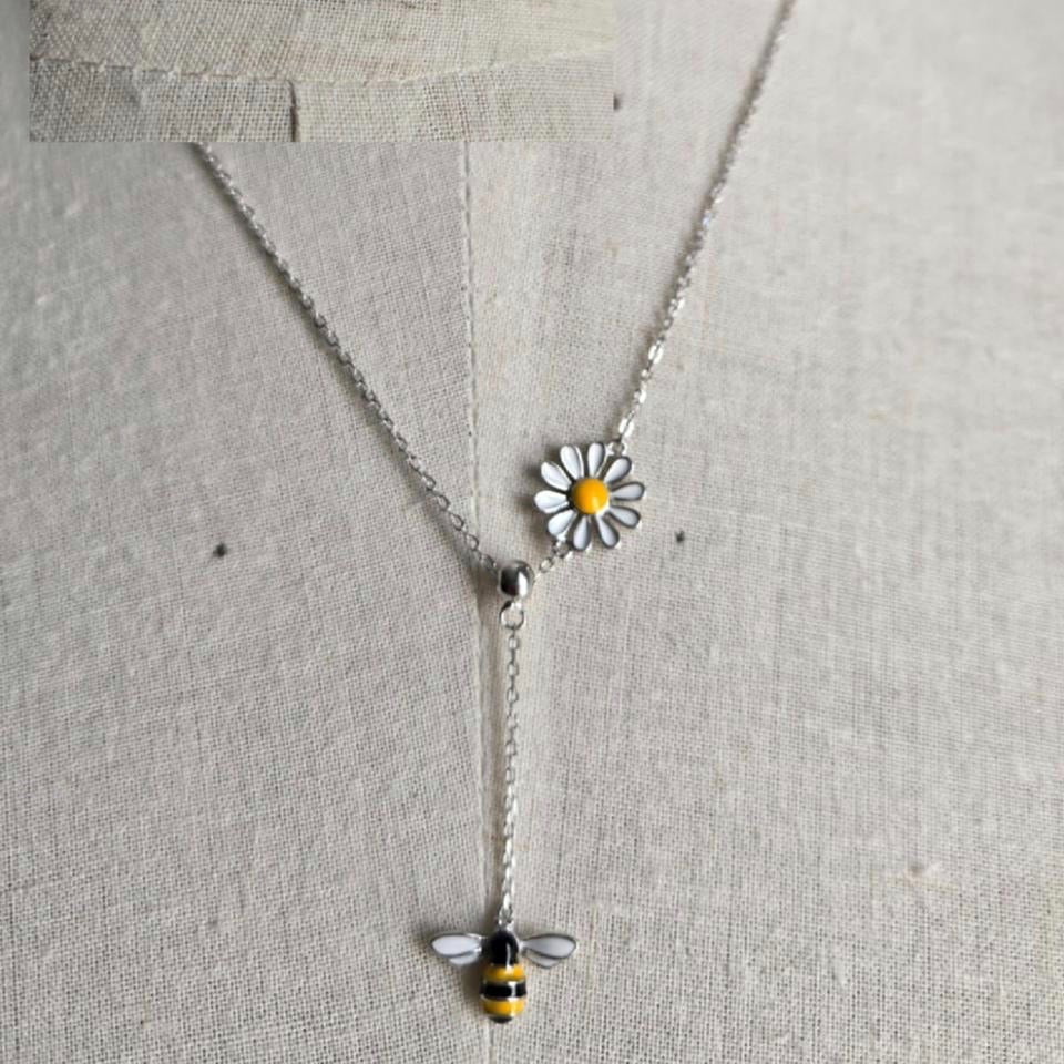 Necklace with a bee and daisy pendant on a gray background