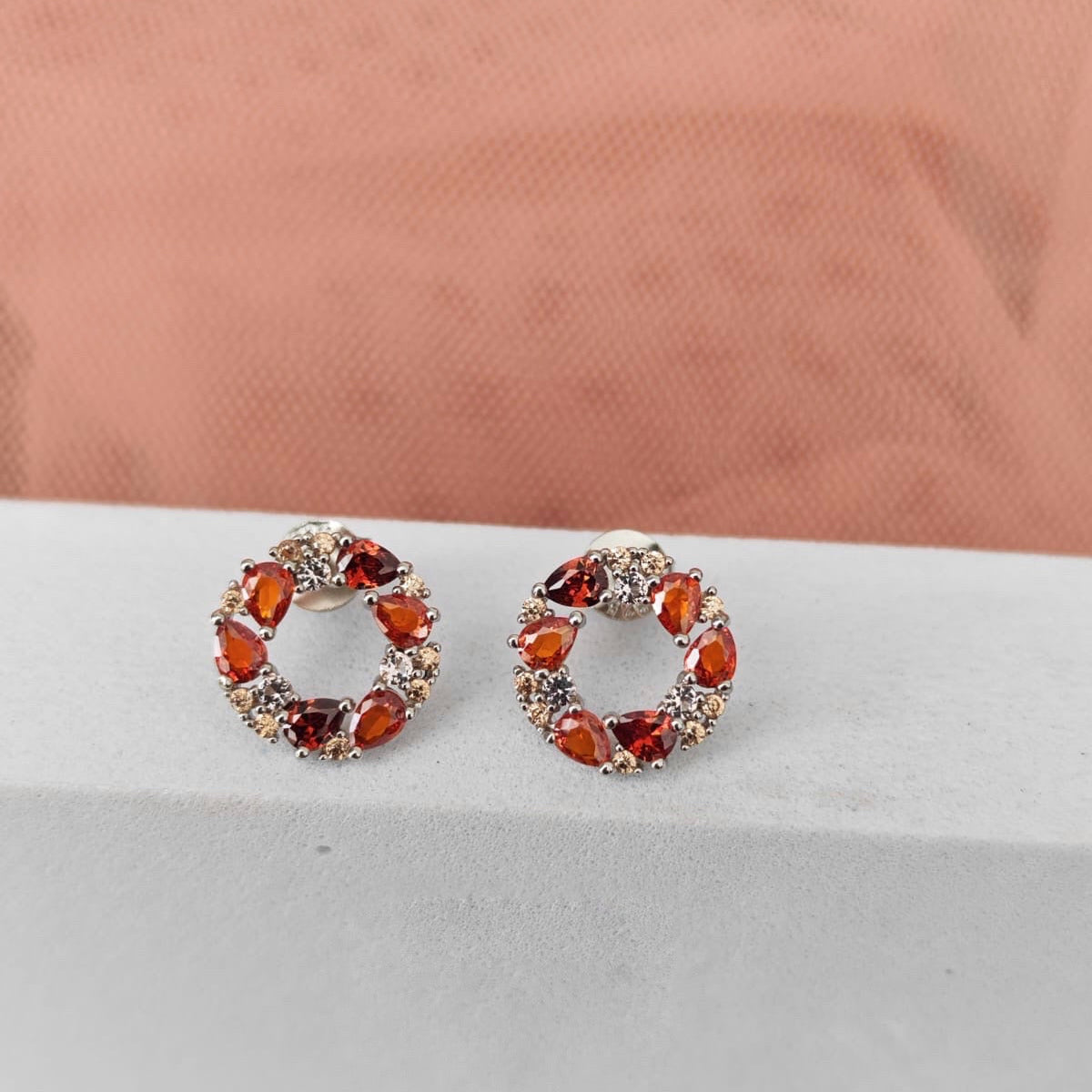 Pair of earrings with red gemstones on a white surface
