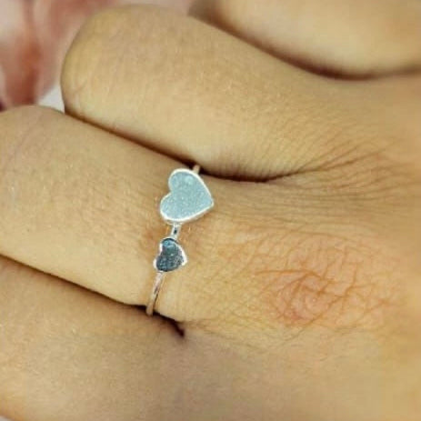 A woman's hand displaying a sterling silver double heart ring on her finger.