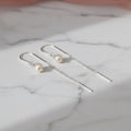 Silver earrings with pearls on a light surface