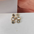 Set of gold earrings with clear gemstones on a white surface