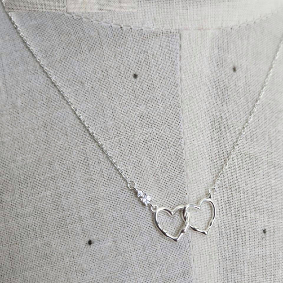 Silver necklace with heart pendants on a textured gray fabric background