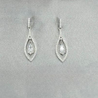 A pair of silver drop earrings with cubic zirconia, displayed against a neutral background with a floral motif.