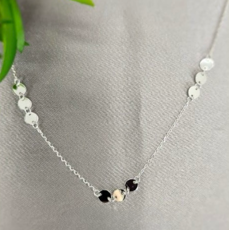 A sterling silver necklace with a group of three metallic disc pendants displayed on a mannequin's neck.