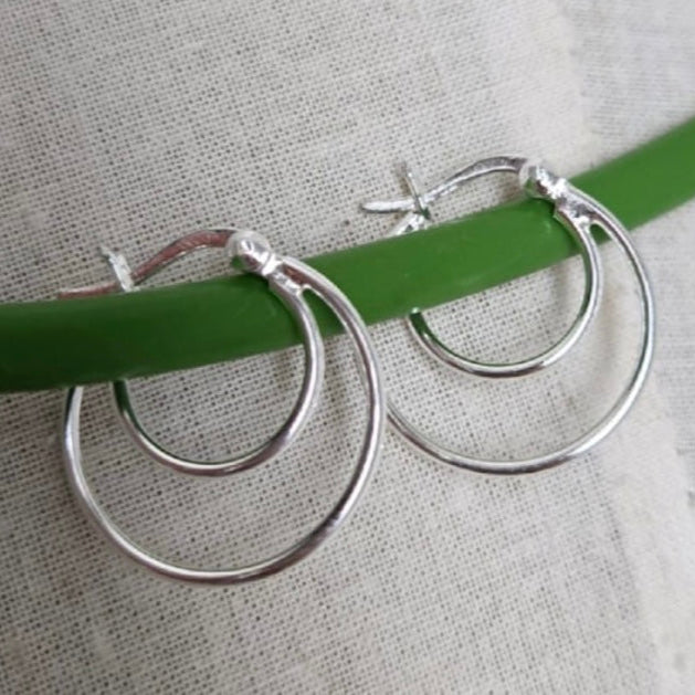 Silver hoop earrings on a green stick with measurement details.