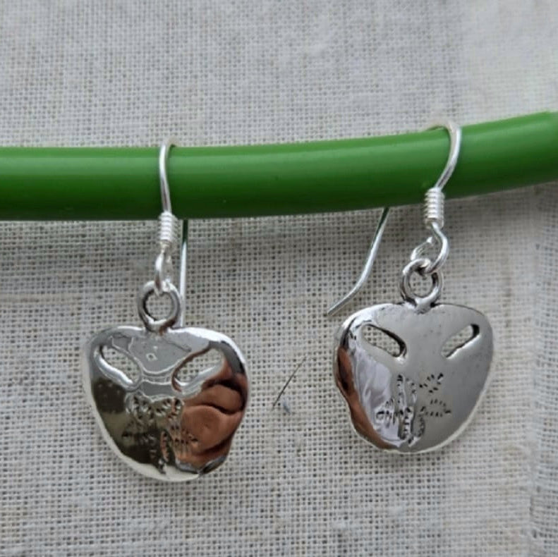 Silver heart-shaped earrings with engraved designs on a gray background