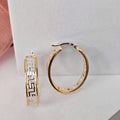 Gold hoop earrings on a light gray surface