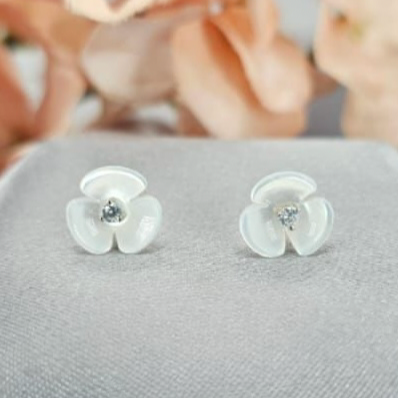 A pair of sterling silver stud earrings featuring a mother of pearl flower design with cubic zirconia accents.