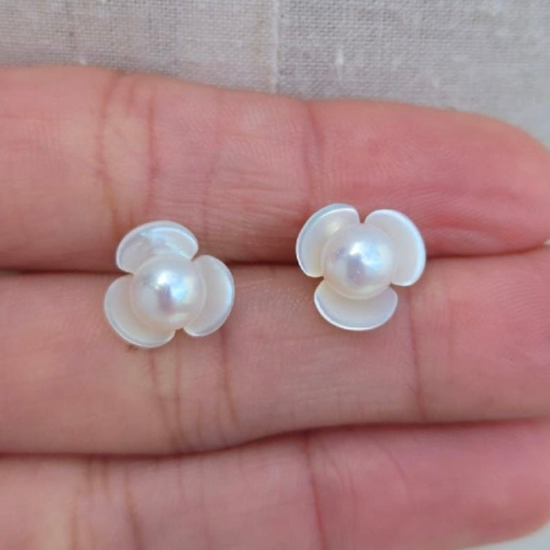 Flower-shaped earrings with pearls on a hand