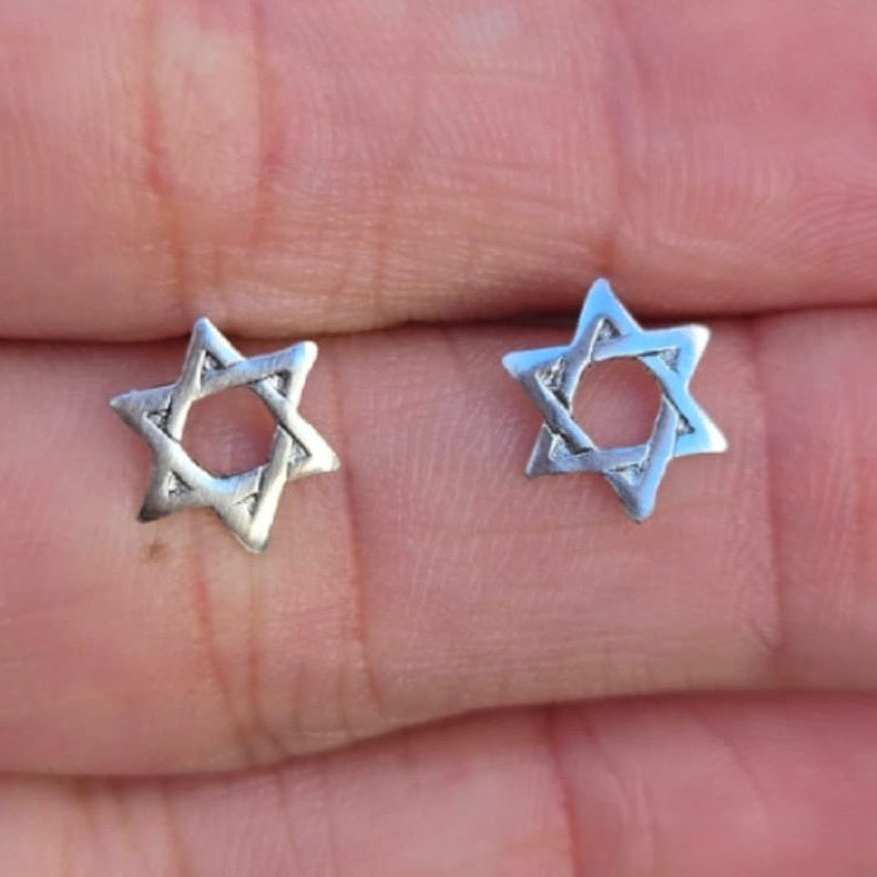 Silver star-shaped earrings on a hand