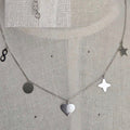 Silver necklace with heart and star pendants on a textured gray background