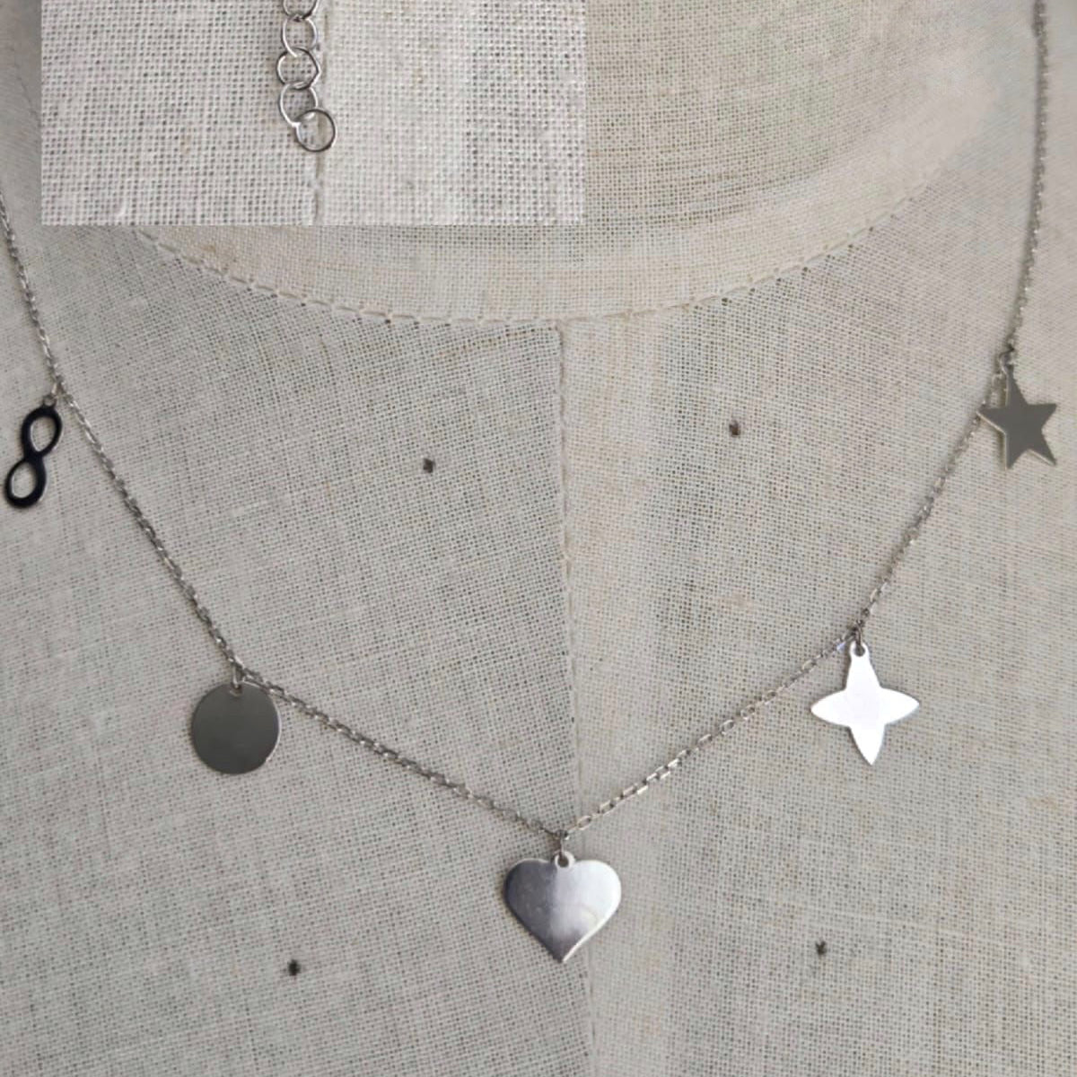 Silver necklace with heart and star pendants on a textured gray background