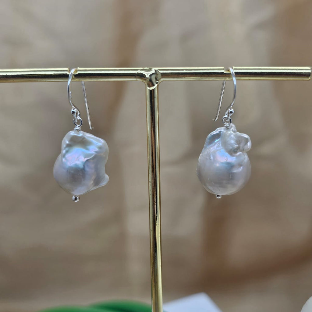 Pearl earrings on a gold stand with a blurred background