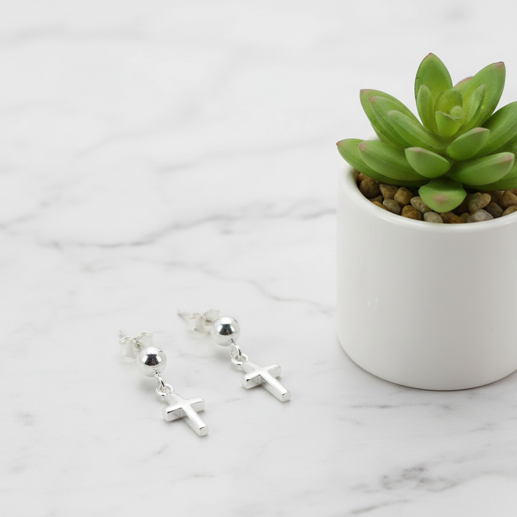 Sterling silver cross earrings displayed in a white vase with a plant background.