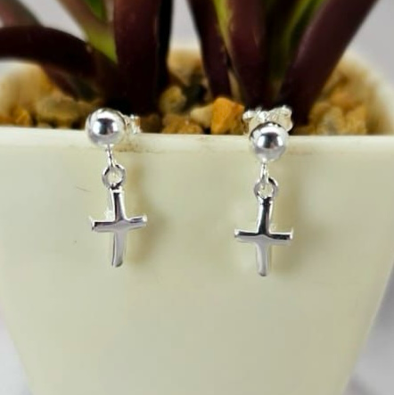 Sterling silver cross earrings displayed in a white vase with a plant background.