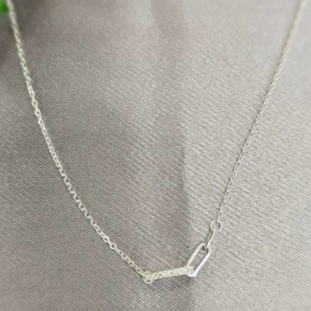 A sterling silver necklace with Gucci links displayed on a gray background.