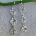 Silver spiral earrings on a light gray fabric background