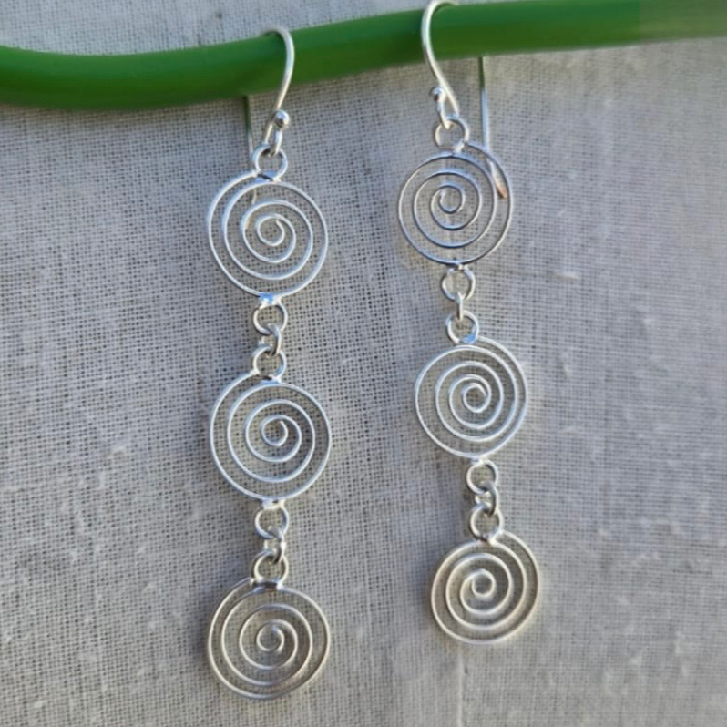 Silver spiral earrings on a light gray fabric background