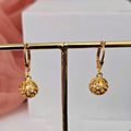 Gold earrings on a display stand with a blurred background