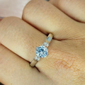 A sterling silver ring with a large cubic zirconia stone in the center, displayed on a person's finger.