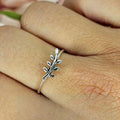 A Sterling silver ring with a tiny branch design, worn on a person's finger.