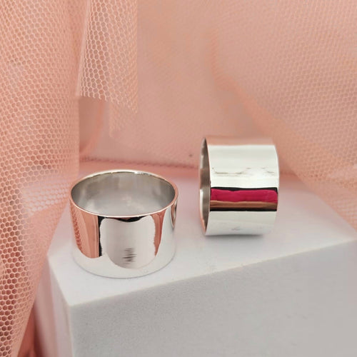 Two silver cylindrical objects on a white platform with a pink fabric background