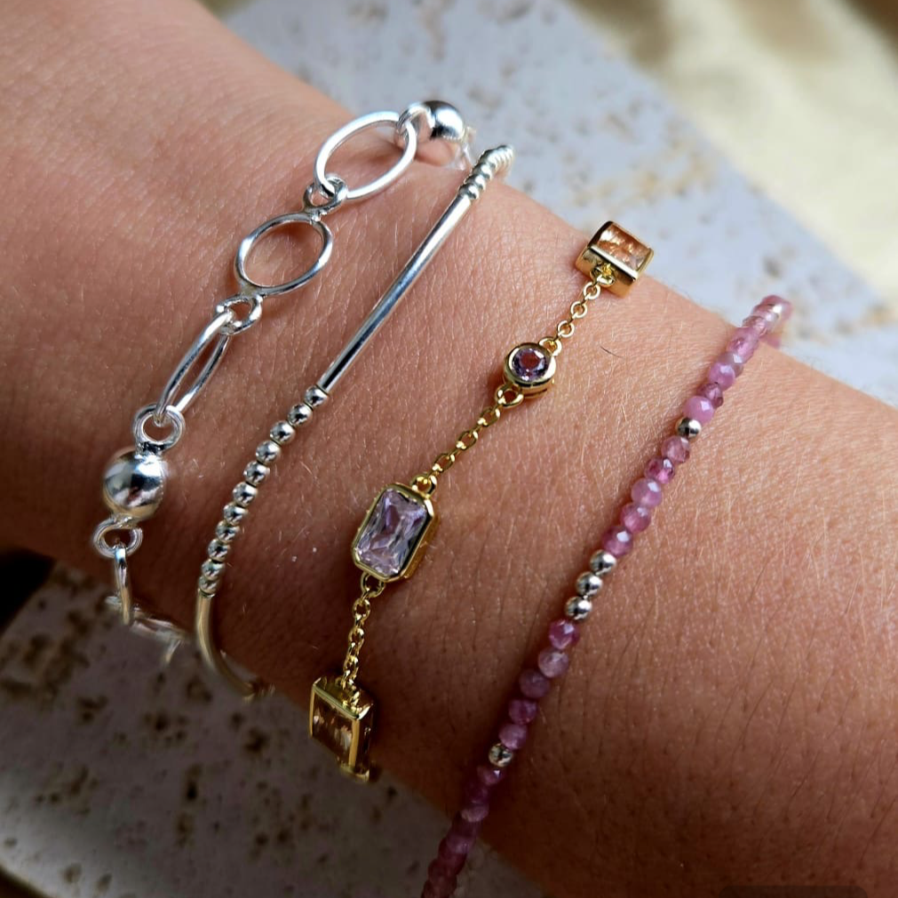 Three bracelets on a wrist with a neutral background