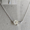 Silver necklace with a floral pendant on a textured fabric background