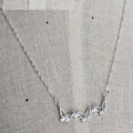 Silver necklace with floral design on a gray fabric background